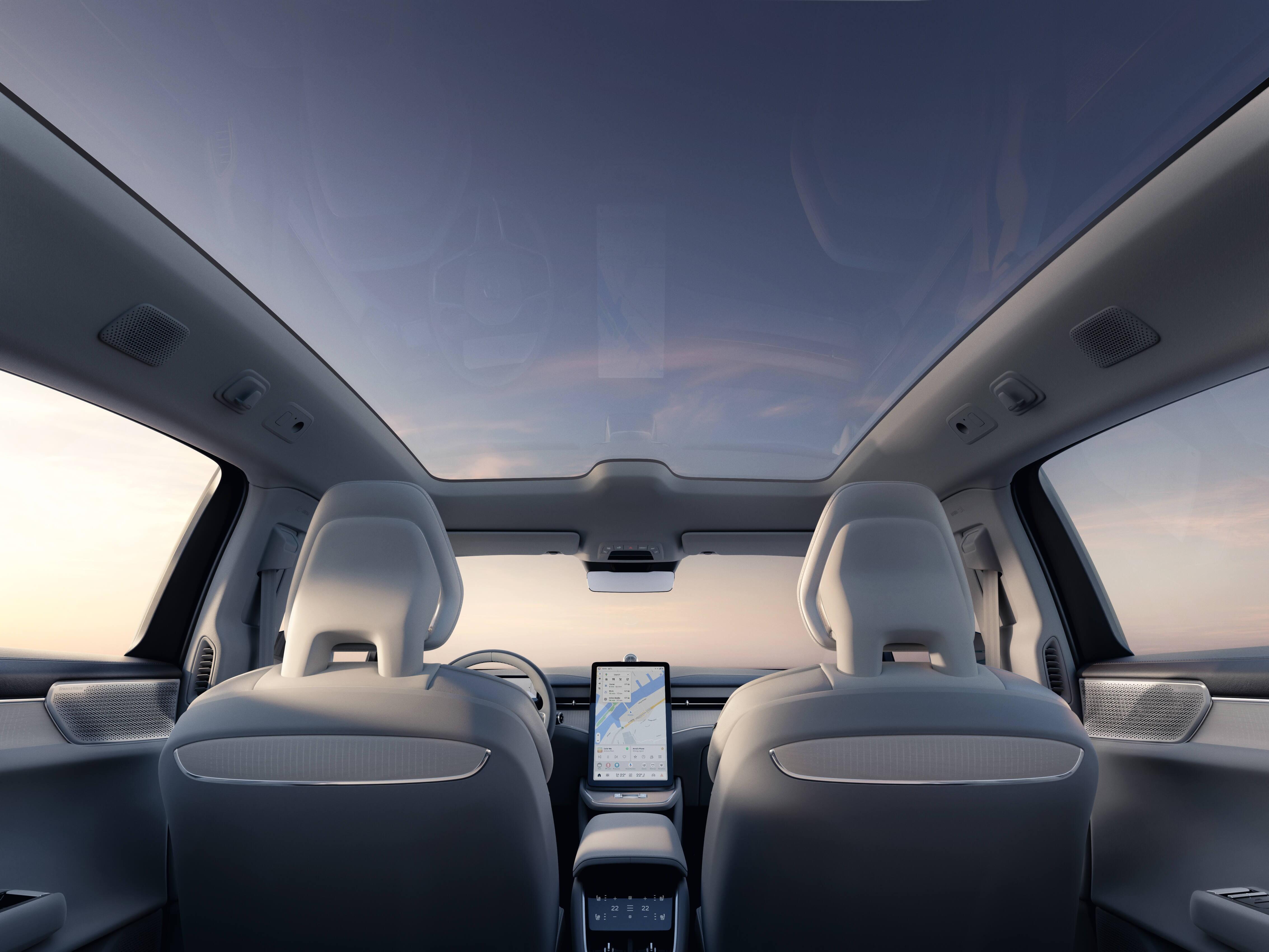 Car interior viewed from the back seats, including panoramic window-roof and large vertical driver's screen display