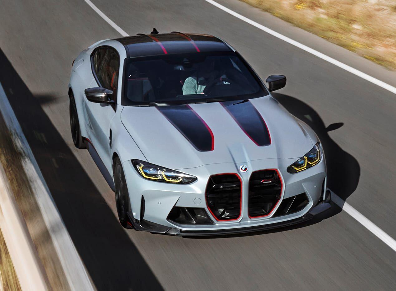 A grey BMW sports car with black and red accents, driving on a narrow road