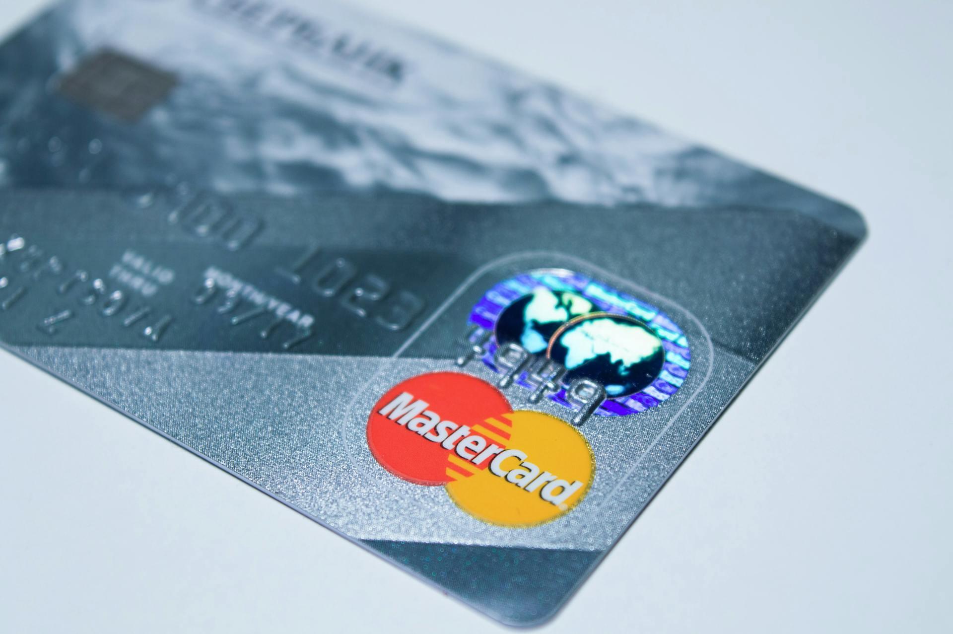 A silver credit card on a white table with the Mastercard logo visible
