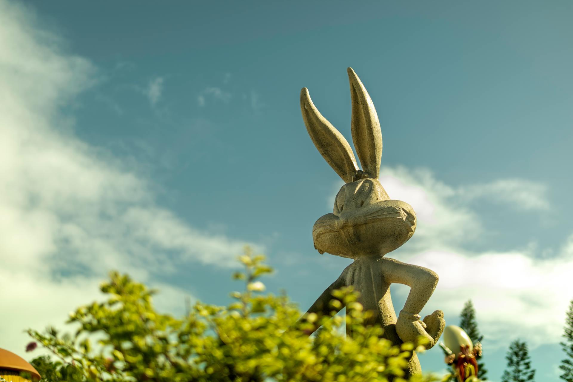 A stone statue of Bugs Bunny looming over a green bush