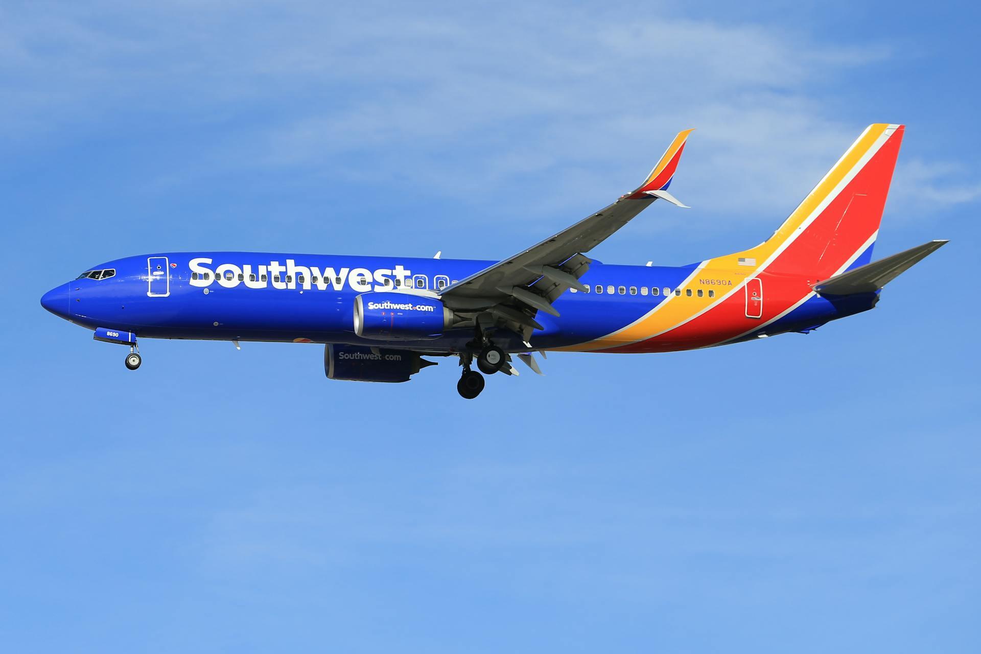 A dark blue plane with a yellow and orange tail with "Southwest" on the side, flying in a blue sky