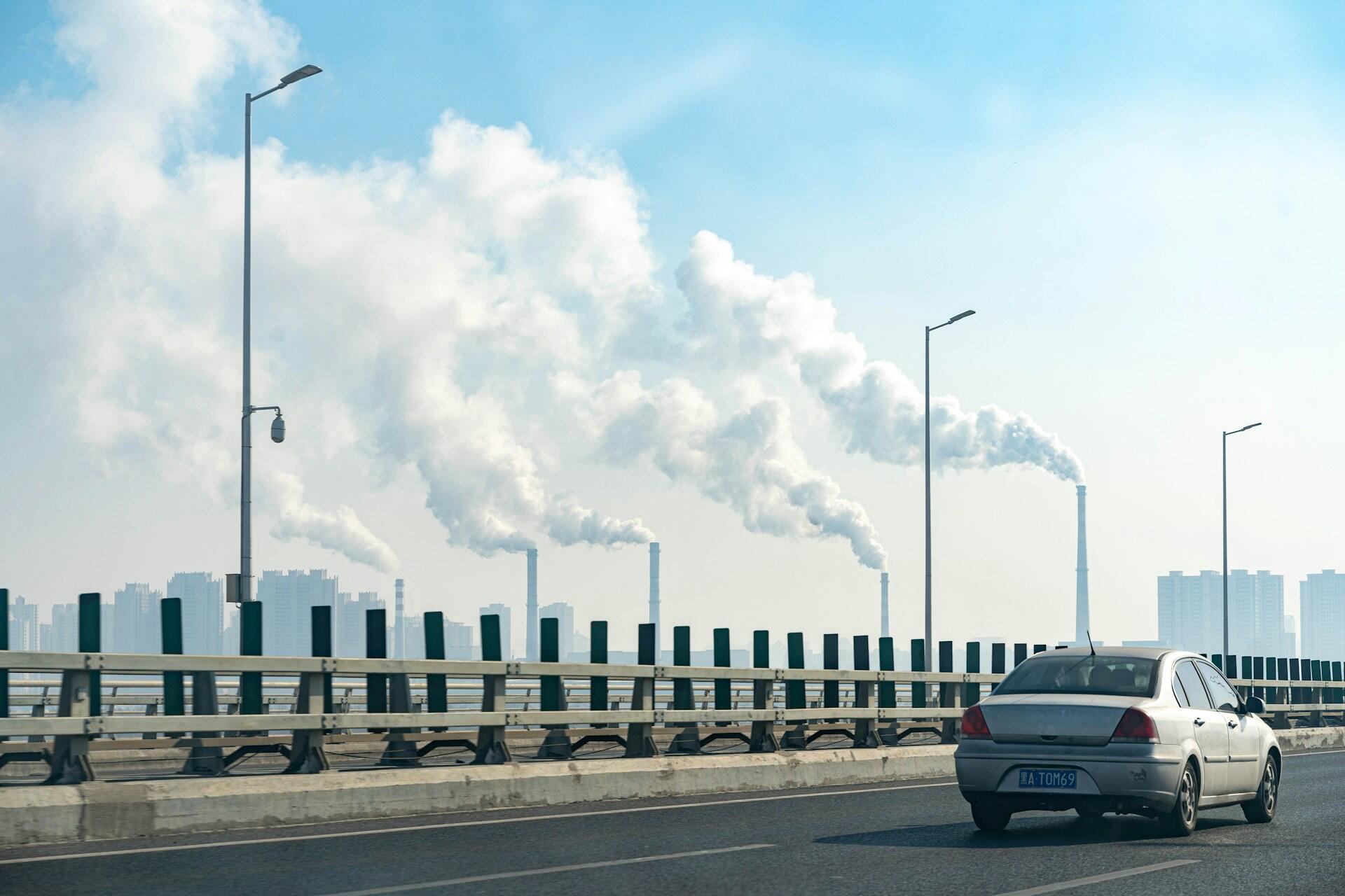 A car driving on a road with a large cloud of smoke behind it.