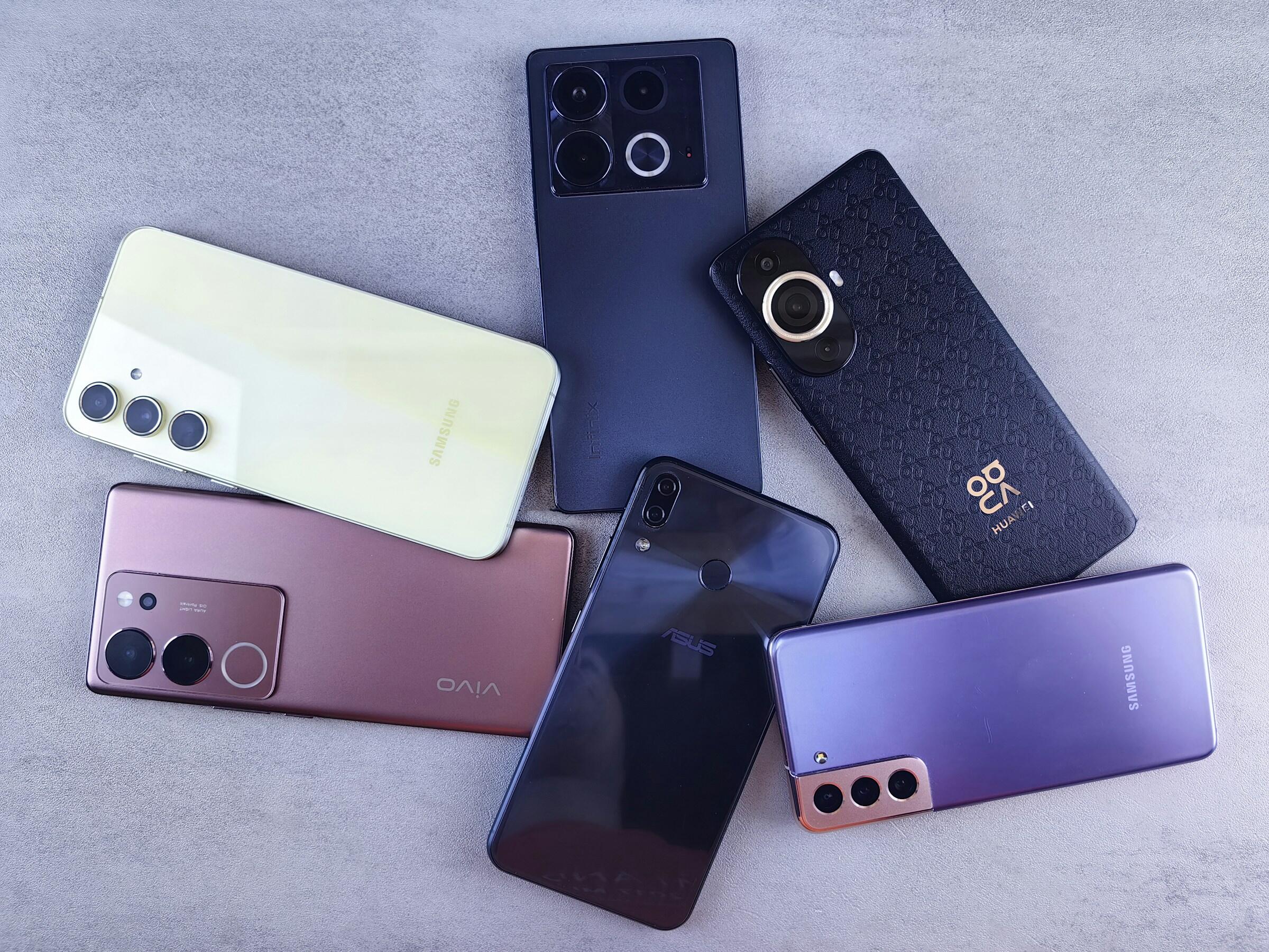 Six smartphones face-down on a grey surface