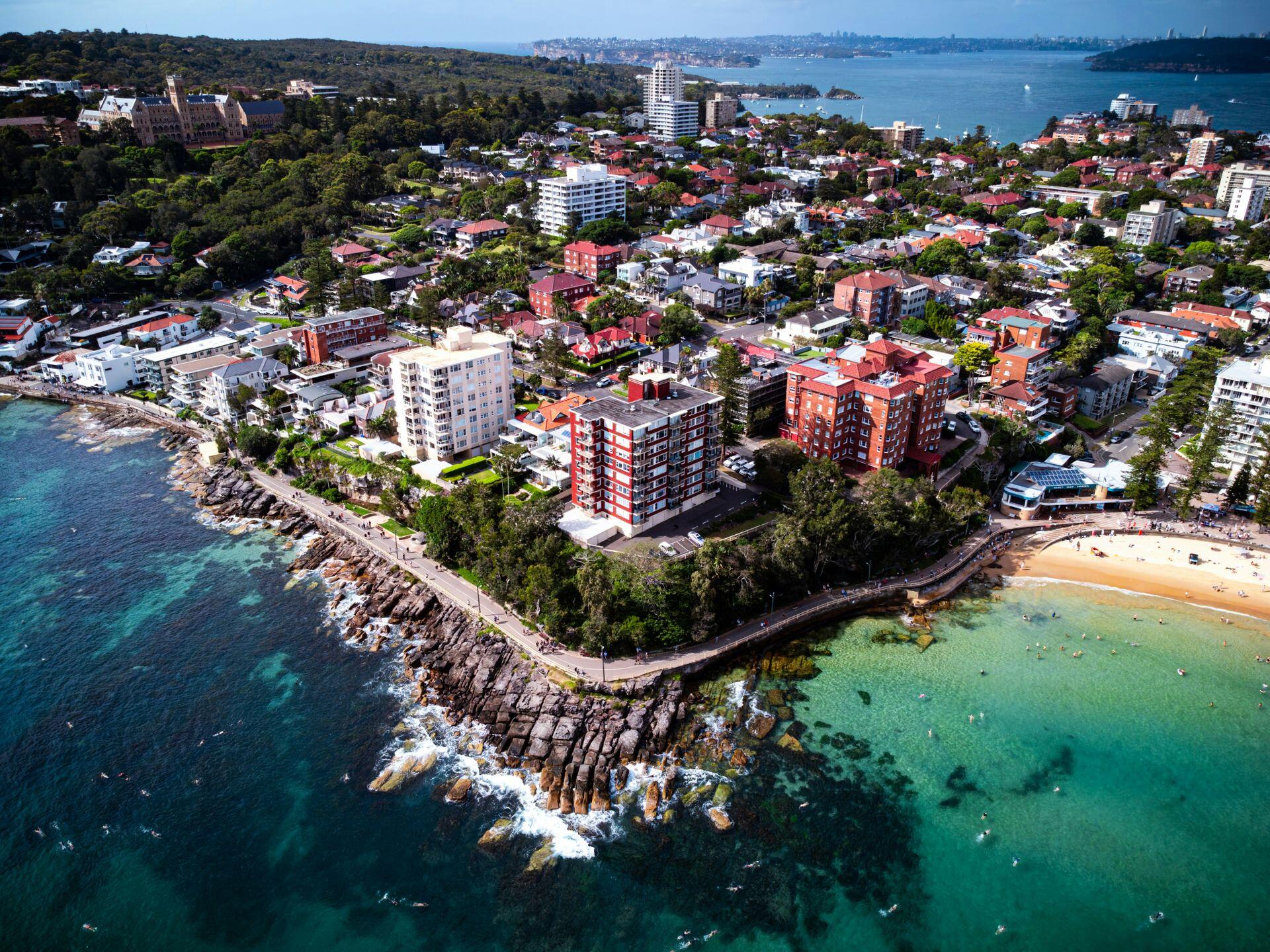 Stunning aerial view of Manly Beach in Sydney, showcasing the coastal cityscape with greenery.