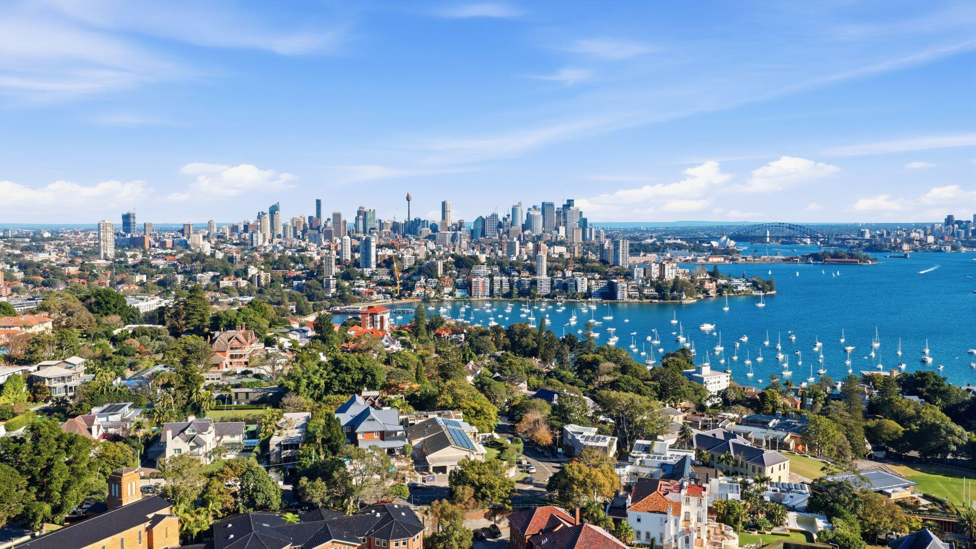 Aerial view of Sydney skyline with the harbour and cityscape on a sunny day.