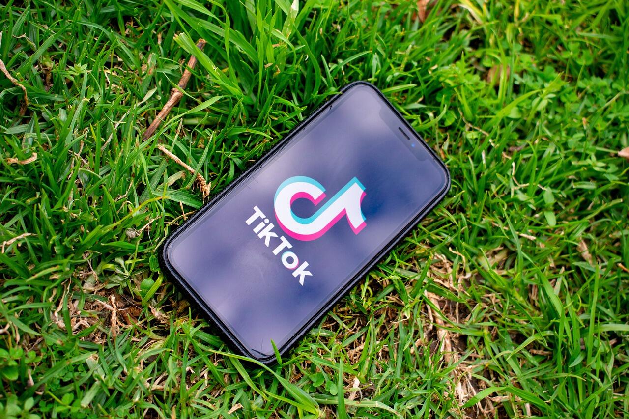 Phone showing TikTok app on the grass.