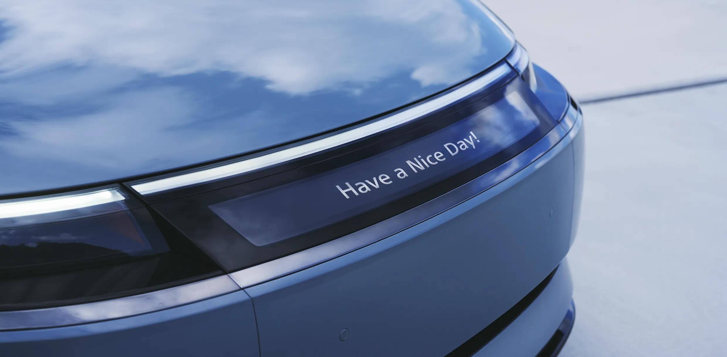 A small horizontal screen on the lower hood of the Afeela 1 SUV, reading "Have a Nice Day!"