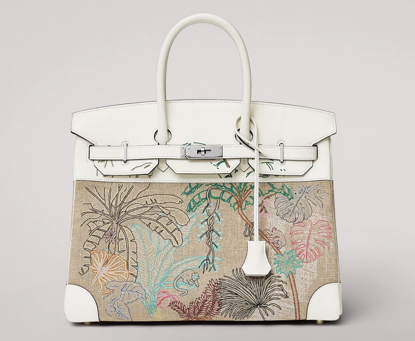 A white and beige bag with a leather handle and tropical stitching