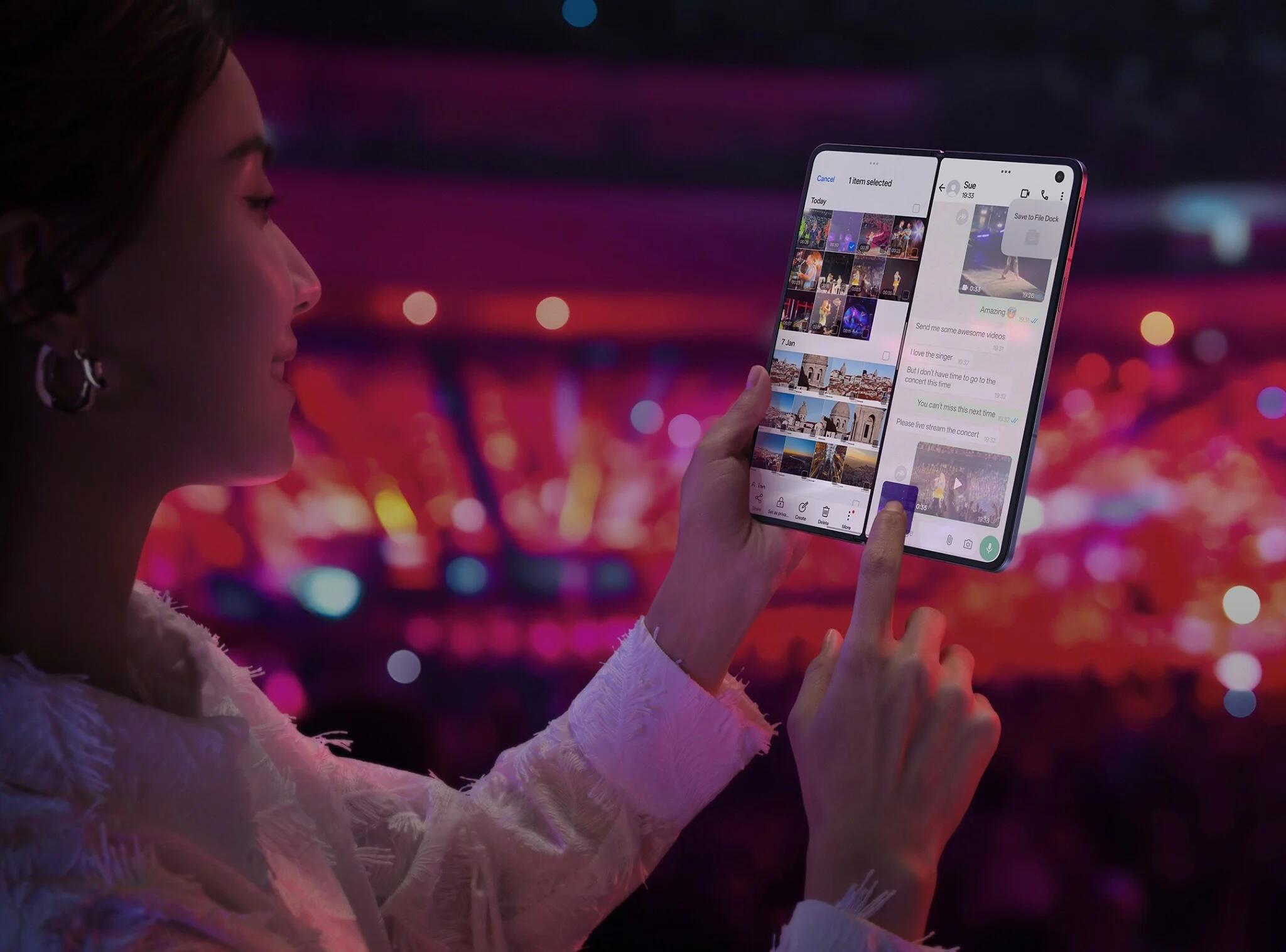 A person holding up an unfolded foldable phone so the screen is visible, with a different app open on each half of the screen